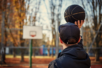 Rear view of a basketball player, shooting at basket outdoor.