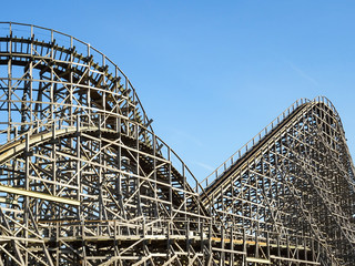 A large wooden roller coaster at an amusement park. thrill