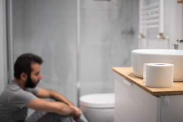 Hombre en el baño intentando vomitar en el inodoro