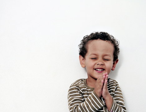boy praying to God stock image with hands held together with closed eyes  stock photo