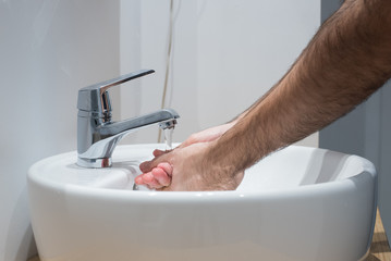 Hombre lavándose las manos en el lavabo