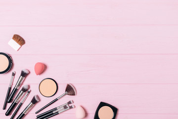 Makeup products and accessories on pink wooden background