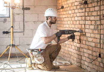 Handyman uses jackhammer, for installation, professional worker on the construction site. The...