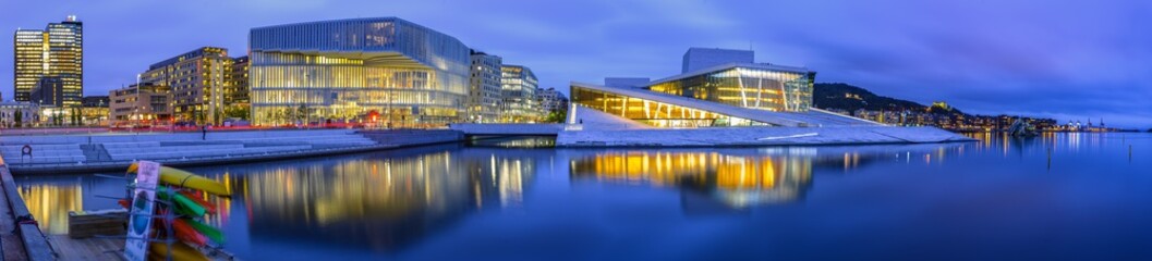 Panoramic shot of illuminated architectural structures in Amsterdam reflected in the sea