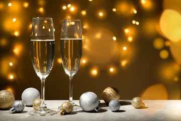 Baubles and champagne glasses on decorated background. Bokeh effect