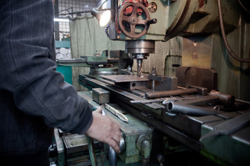 closeup of metallic lathe working against factory industrial interior background