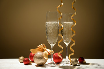 Baubles and champagne glasses against golden background, space for text