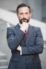 Contemplative glance of successful businessman with his fist raised to chin