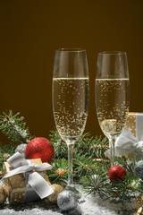 Champagne glasses and baubles against golden background, space for text