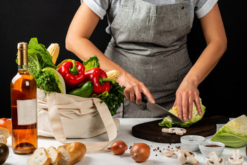Cooking healthy food in home kitchen concept. Woman in an apron cuts vegetables.