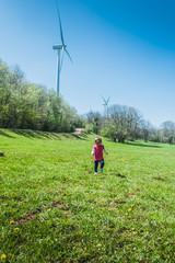Little girl running in a field in front of a windmill