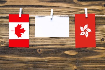 Hanging flags of Canada and Hong Kong attached to rope with clothes pins with copy space on white...