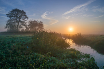 Fototapeta na wymiar Wschód słońca, nizinna rzeka i łąka