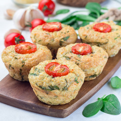 Savory muffins with quinoa, cheese and spinach topped with tomato, on wooden board, square format