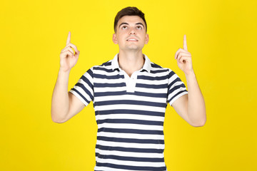 Young man showing fingers up on yellow background