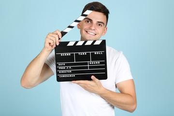 Young man with black clapper board on blue background