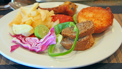 Dish of french fries with pieces of meat, lime, cut pieces of vegetables