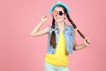Beautiful young girl with sweet lollipop on pink background