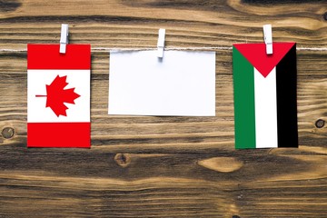 Hanging flags of Canada and Palestine attached to rope with clothes pins with copy space on white...