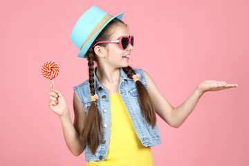 Beautiful young girl with sweet lollipop on pink background