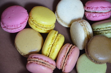 Colourful tasty macaroons in a row. macaroons of different colors on a brown background