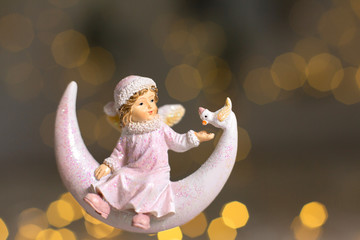 Decorative figurines of a Christmas theme. Statuette of an angel on a crescent moon. Christmas tree...