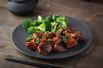teriyaki chicken and broccoli on black plate