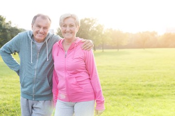 Cheerful senior man and woman in sportswear standing at park