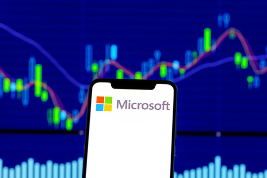 Microsoft logo is seen on an smartphone over stock chart