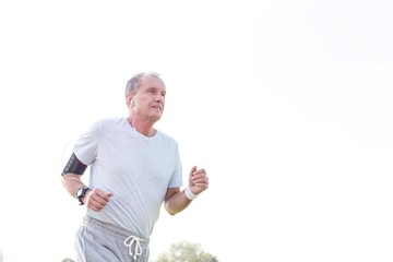 Dedicated senior man jogging against sky