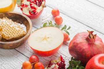 Rosh hashanah - jewish New Year holiday concept. Traditional symbols: Honey jar and fresh apples with pomegranate and shofar -horn on a white background. Copy space for text. View from above