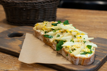 Close-up of the delicious sandwich with white asparagus and cooked egg laying on the wooden board.