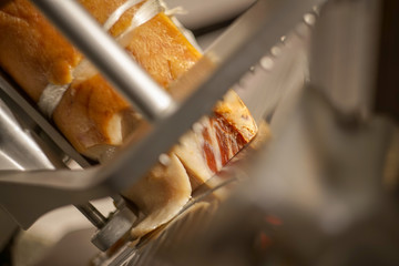 Close up shot of prosciutto ham on slicing machine