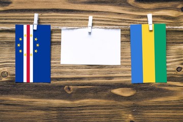 Hanging flags of Cape Verde and Gabon attached to rope with clothes pins with copy space on white...