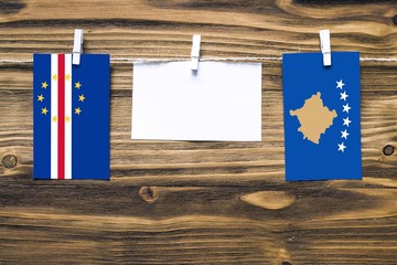 Hanging flags of Cape Verde and Kosovo attached to rope with clothes pins with copy space on white...