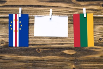 Hanging flags of Cape Verde and Lithuania attached to rope with clothes pins with copy space on white note paper on wooden background.Diplomatic relations between countries.