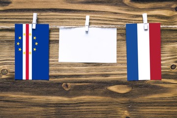 Hanging flags of Cape Verde and Netherlands attached to rope with clothes pins with copy space on white note paper on wooden background.Diplomatic relations between countries.