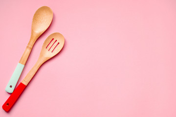 Two wooden spoons on a pink background, top view, copy space