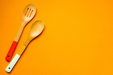 Two wooden spoons on a orange background, top view, copy space