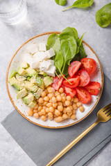 Buddha Bowl with Avocado, chickpea, feta cheese, fresh spinach, Tomatoes and glass of water. Concept for healthy vegetarian detox balanced meal. Top view. Copy space.