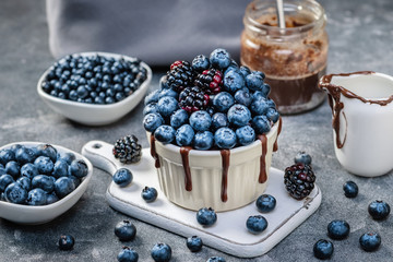 Chocolate mug cake with blueberries and blackberries in a white ceramic mug on white background