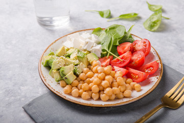 Buddha Bowl with Avocado, chickpea, feta cheese, fresh spinach, Tomatoes and glass of water. Concept for healthy vegetarian detox balanced meal. Top view. Copy space.