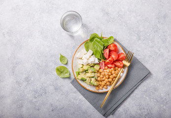 Buddha Bowl with Avocado, chickpea, feta cheese, fresh spinach, Tomatoes and glass of water. Concept for healthy vegetarian detox balanced meal. Top view. Copy space.