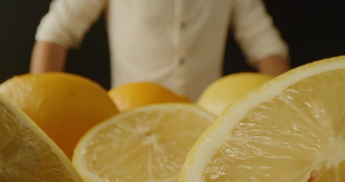 Macro shot of lemons, plenty of lemons, dramatic lightning, red epic, slow motion, cutter in half, chef stands in background, ready to cook