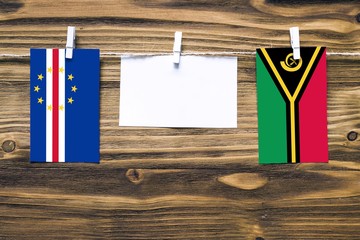 Hanging flags of Cape Verde and Vanuatu attached to rope with clothes pins with copy space on white...