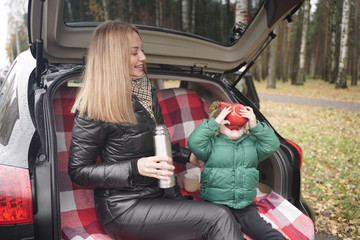 Family adventure - family on autumn camp. Young beauty mom and little child had picnic in back of car near the fall park