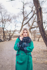 Pensive serious blonde girl walks in the park reflecting on problems