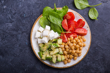 Buddha Bowl with Avocado, chickpea, feta cheese,  fresh spinach, Tomatoes and glass of water. Concept for  healthy vegetarian detox balanced  meal. Top view. Copy space.