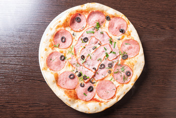 Cheap pizza with pepperoni, ham, olives and herbs.