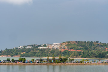Ko Samui Island, Thailand - March 18, 2019: Looking northeast from Wat Phra Yai Buddhist Temple on Ko Phan. Dam pier in front and hills with white and red roofed villas in tourist resorts under blue s